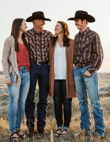 the Buchholz ranching family standing on a rocky hillside smiling at each other